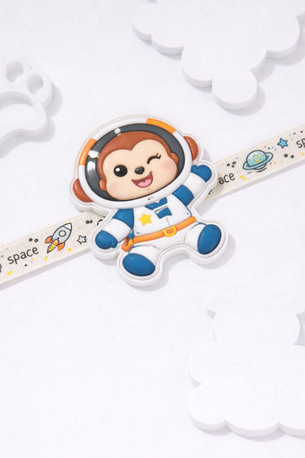 Cute astronaut cartoon kids rakhi with space-themed strap featuring rockets and planets.
